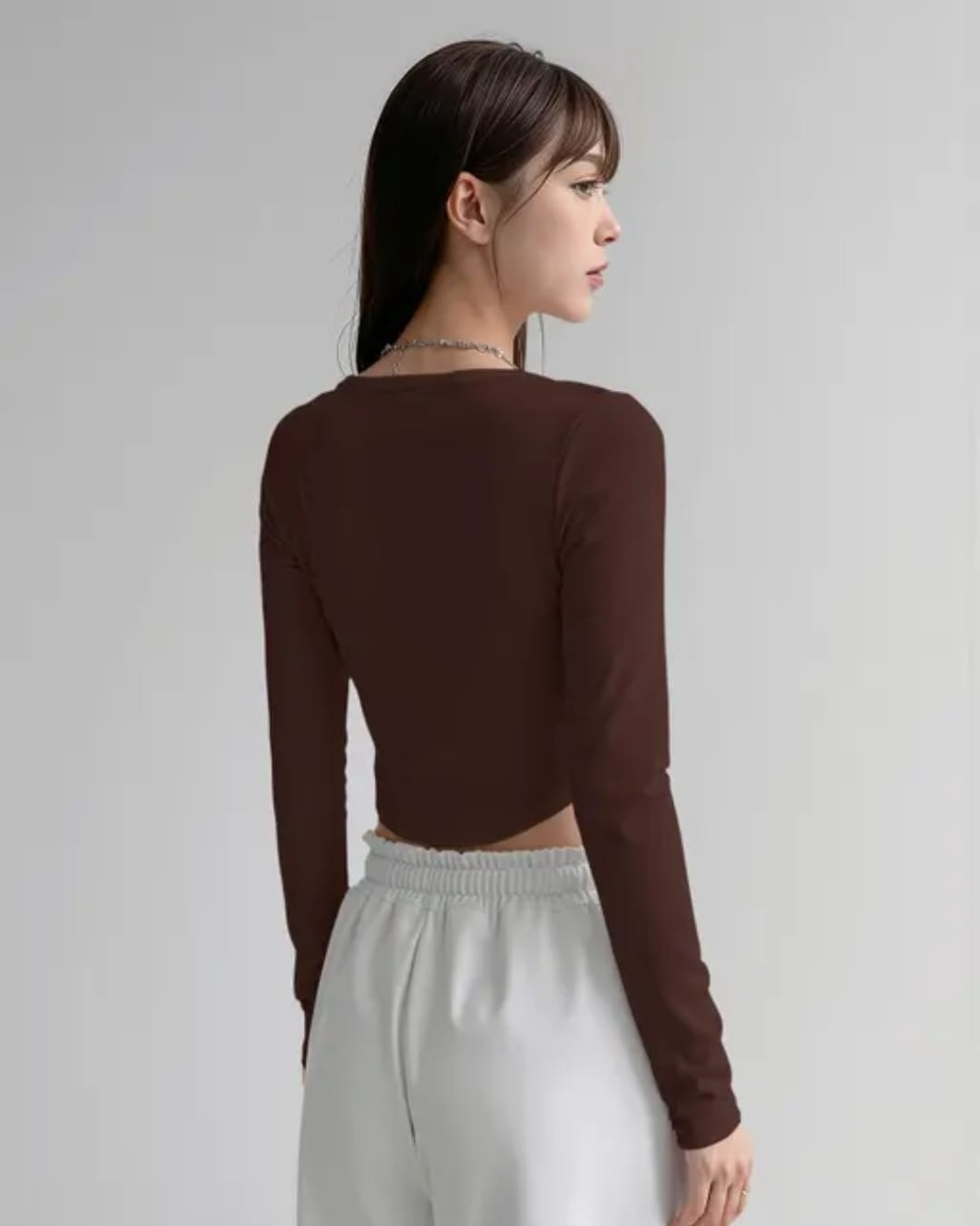 brown crop top 2 age Alt Text: Woman wearing a chocolate brown square neck full sleeve corset style ribbed crop top