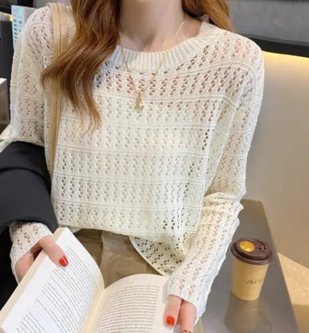 Woman wearing a cream crochet knit long sleeve sweater with an open-knit design