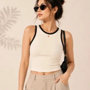 Woman wearing a cream sleeveless crop tank top with black contrast trim