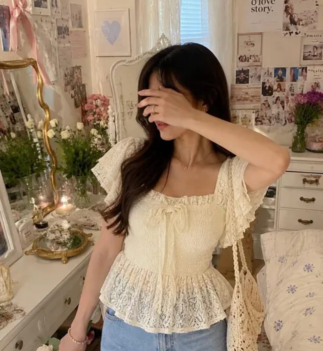 Woman wearing an ivory smocked peplum top with flutter sleeves, a square neckline, and a lace hem