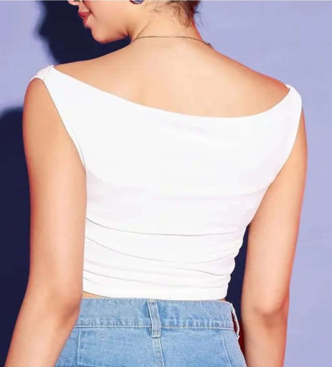 Woman wearing a white off-shoulder slim-fit draped top paired with blue denim jeans