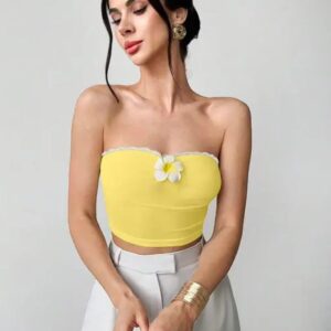 Woman wearing a yellow strapless tube crop top with white lace trim and floral detail